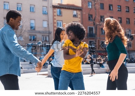 Multi ethnic young friends dancing and smiling a city square, group of happy people having fun together