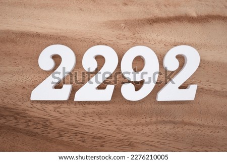 White number 2292 on a brown and light brown wooden background.
