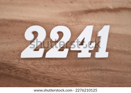 White number 2241 on a brown and light brown wooden background.
