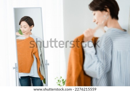 Young woman choosing clothes in front of the mirror Fashion image