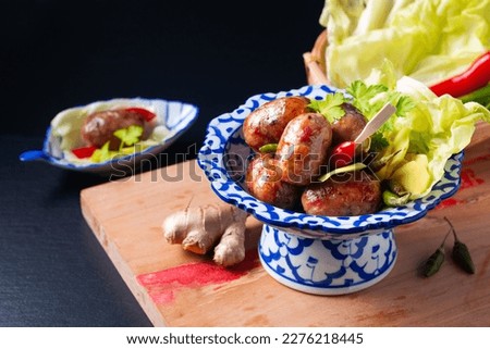 Food concept Sai krok Isan or Isaan Thai-Laos fermented pork and rice sausages in Tradition thai ceramic pedestal plate on black background with copy space Royalty-Free Stock Photo #2276218445