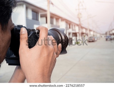 Close up hands of Young Asian photographer taking pictures of housing estates. Property and real estate concept.