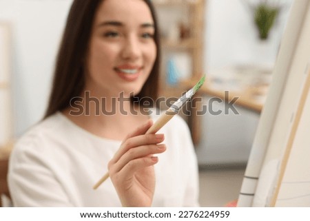 Beautiful young woman painting in studio, selective focus. Creative hobby