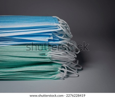 Biscay green and blue surgical masks overlaid in layers on gray background, Bacteria protection concept.