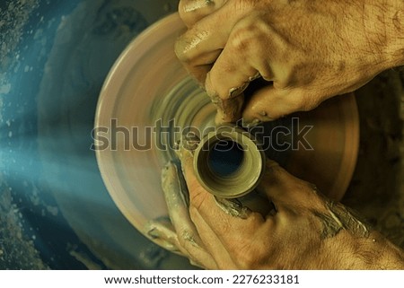 Close-up of a potter's hands at work on a potter's wheel. Top view, dark background, muted colors Royalty-Free Stock Photo #2276233181