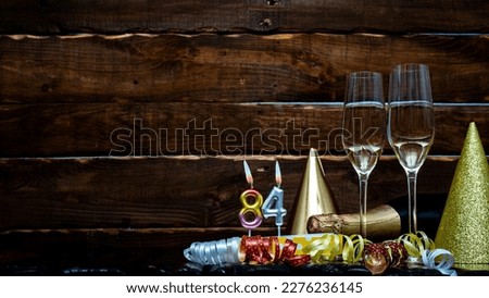 Solemn background for the anniversary with the number  84. Happy birthday background on brown wooden background with champagne bottle and champagne glasses. Beautiful holiday decorations copy space.