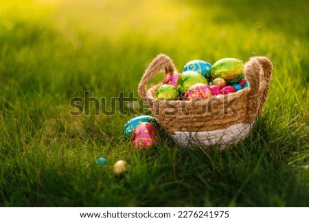 Easter eggs in a basket in green grass. Spring season traditional egg hunt colorful decorated eggs in a wicker basket. 