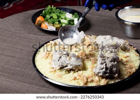 Jordanian Mansaf traditional food. with rice and meet. Jameed Yogurt on top of it and almond. Photo taken on a wodden table. Side View Photo. Royalty-Free Stock Photo #2276250343