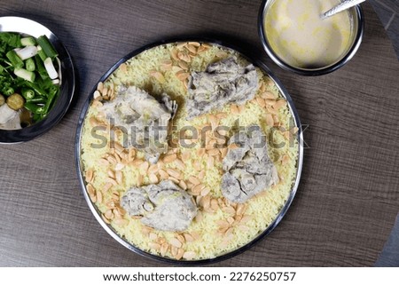 Jordanian Mansaf traditional food. with rice and meet. Jameed Yogurt on top of it and almond. Photo taken on a wodden table. Top View Photo. Royalty-Free Stock Photo #2276250757