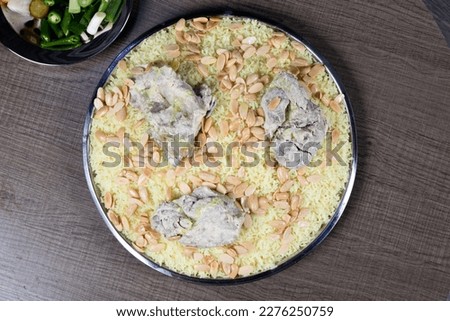 Jordanian Mansaf traditional food. with rice and meet. Jameed Yogurt on top of it and almond. Photo taken on a wodden table. Top View Photo. Royalty-Free Stock Photo #2276250759