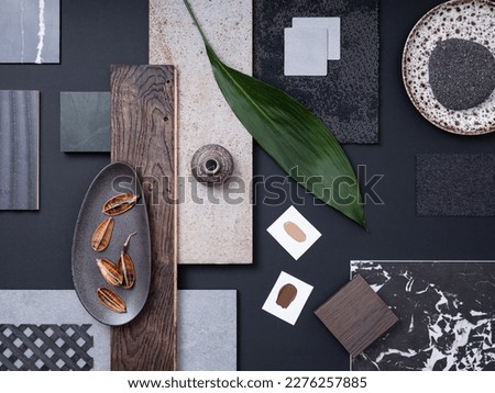 Aesthetic  flat lay composition in grey and navy color palette with textile and paint samples, lamella panels, leaves and tiles. Architect and interior designer moodboard. Top view. Copy space. 