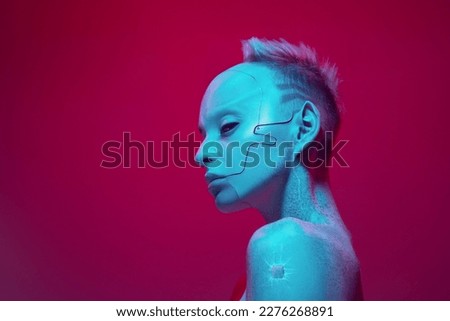 Young girl in image of futuristic cyborg robot with bare shoulders against pink studio background in neon light. Digitalization. Cyberpunk style. Concept of futurism, surrealism, digital world, robot