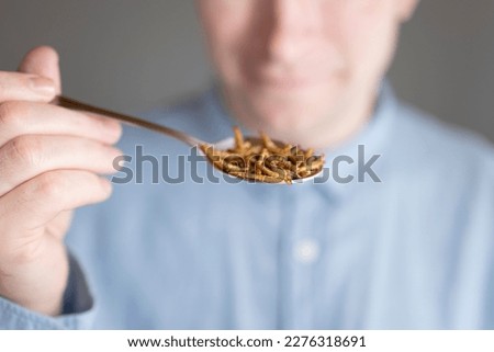 Meal worm foods.Laughing man with a spoon of worms.