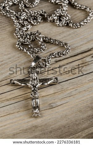 Close up of a silver Crucifix necklace isolated on a wooden background with copy space