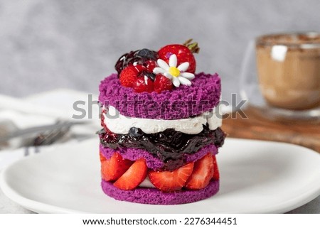 Layered fruit cake. Cake with strawberries, raspberry sauce and cream on a stone background. Patisserie desserts. Close up Royalty-Free Stock Photo #2276344451