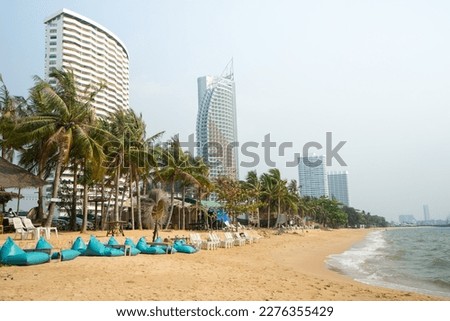 Seats and hotel on the beach with row of coconut trees for tourist to walk on holiday at Pataya beach,Thailand. Royalty-Free Stock Photo #2276355429