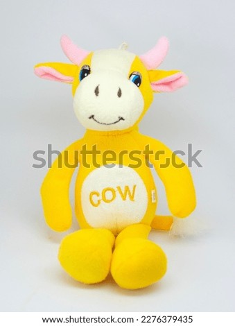 stuffed cow sitting and smiling isolated against white background , yellow cow white belly and stuffed pink ear. toy for kids