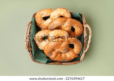Basket with tasty pretzels on color background