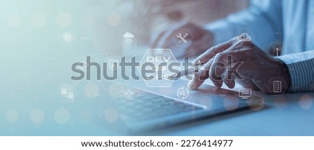 Software development, IT operations, agile programming, Concept with dev ops icon on a computer screen and project manager, coder or sysadmin typing on a keyboard, high software quality Royalty-Free Stock Photo #2276414977