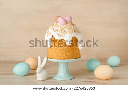 Stand with Easter cake, painted eggs and bunny on wooden background Royalty-Free Stock Photo #2276425853