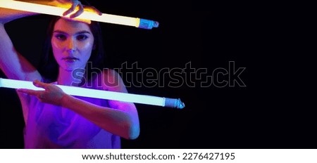 Toned portrait of beautiful woman with neon lamps on dark background with space fro text