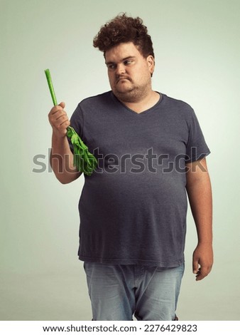 The hardest part of dieting. an overweight man holding a celery stick. Royalty-Free Stock Photo #2276429823