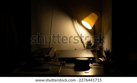 An aesthetic picture of a working table with a warm lit lamp, a laptop and 3 plants