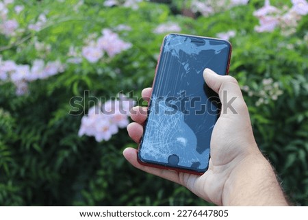 Red Smartphone, broken glass, garden background