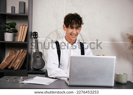Young man drinking morning coffee in the office. Freelancer with laptop in loft style apartment.