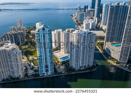 Aerial shot from a drone of the Brickell Key area, with a lot of towers and modern buildings, commercial urban landscape, surrounded by sea and canals, boats sailing, piers, bridges, avenues, blue sky