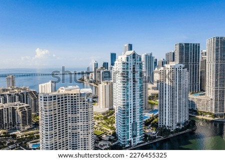 Aerial shot from a drone of the Brickell Key area, with a lot of towers and modern buildings, commercial urban landscape, surrounded by sea and canals, boats sailing, piers, bridges, avenues, blue sky