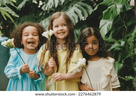 Three little girls in the garden with flowers in their hands. children of different nationalities. Royalty-Free Stock Photo #2276462879
