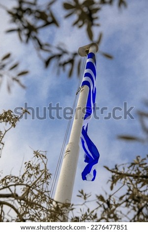 Waving Greek flag between the trees on the top of Lycabettus Hill in Athens