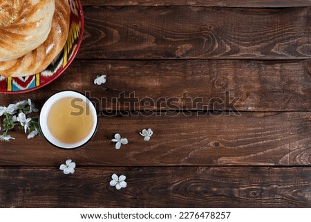 journey cake bread on adras plate and teabowl with white cherry flowers on wooden background. Navruz, Ramadan postcard