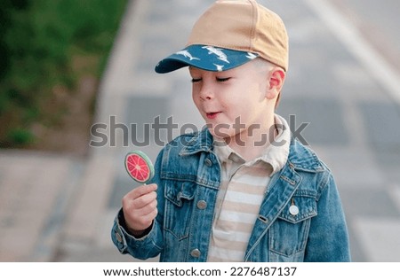Liitle Boy with sweet tasty candy, outdoor.