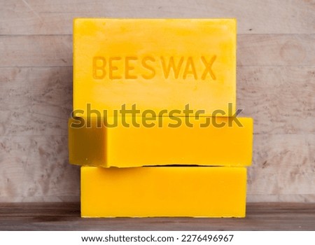 Three bricks of pure bees wax stacked against a wood background Royalty-Free Stock Photo #2276496967