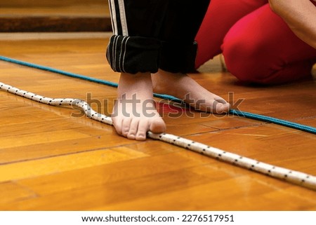The child's left foot in focus. Children's bare feet on a rope. Children's feet close-up, concept of development of fine motor skills, tactile sensations, creativity, children's entertainment. Royalty-Free Stock Photo #2276517951