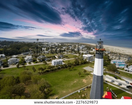 aerial shot of the a gorgeous spring landscape at Tybee Island Beach with the lighthouse, blue ocean water, a brown sandy beach, homes and lush green trees and grass in Tybee Island Georgia USA
