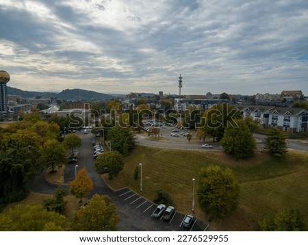 aerial shot of a gorgeous autumn landscape with yellow, red, and green trees and office buildings and apartments in the city skyline with blue sky and clouds