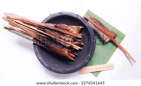 Top view of Smoked fish. Smoked stringray on mortar stone against white background. Fresh. Smoked stringray fillet of Fillet fish. Seafood. Isolated. Fish on banana leaf Royalty-Free Stock Photo #2276541645