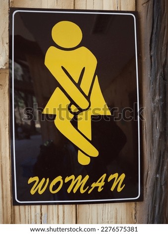 Women's restroom sign on dark brown background.