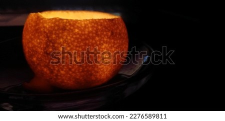 isolated candlelight inside peeled tangerine. Glowing spiral cover. Candlight on black background. Halo around. Golden light with transition circle. isolated light source.Peeled orange. Golden space.