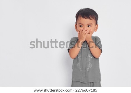 Shocked toddler Asian muslim boy covering mouth with hands and looking at empty space isolated on white studio background Royalty-Free Stock Photo #2276607185