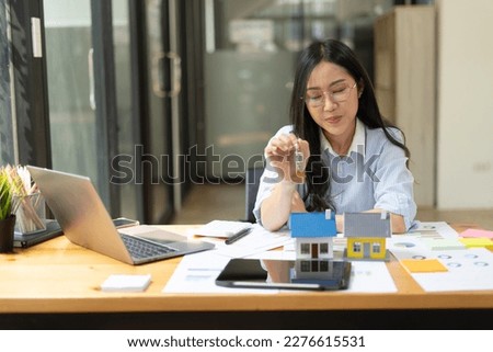 Woman holding house model and house key in hand