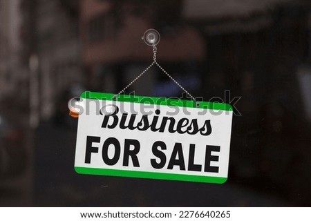 Close-up on a blue open sign in the window of a shop displaying the message: Business for sale. Royalty-Free Stock Photo #2276640265