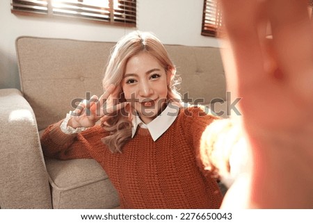 Happy woman smiling while taking a selfie at home.