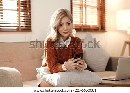 Woman using smart phone for social media laying in her couch