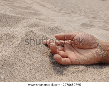 A weak hand rests on the barren sand feeling of despair 
