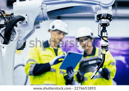 Caucasian american development technician engineer testing artificial intelligence robot arm at high technology research manufactue with equipment. Factory workers working with adept robotic arm.