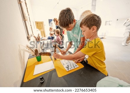 Boys writing with feather quill pen at desk.  Royalty-Free Stock Photo #2276653405